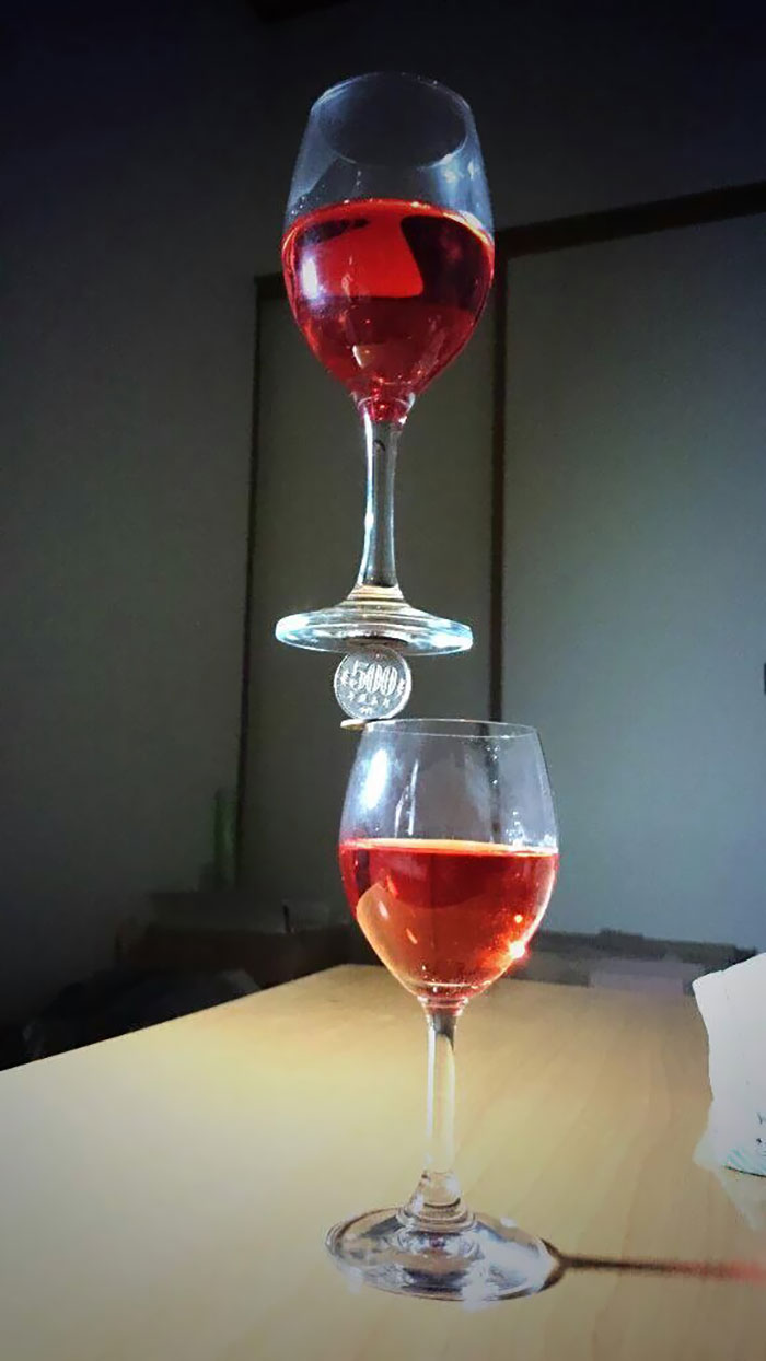 Wine glass balancing on coin balancing on another wine glass