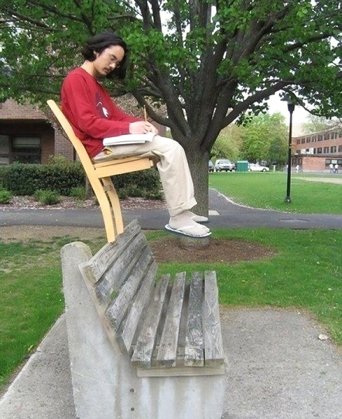 Man sitting in chair with 2 legs on a bench