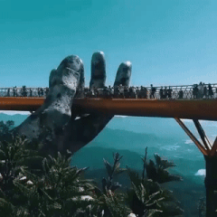 A golden bridge being “lifted” with giant hands in Vietnam.