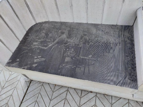 Black and white image etched into a park bench using grooves of varying width