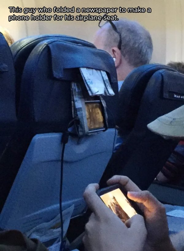 airplane phone holder - This guy who folded a newspaper to make a phone holder for his airplane seat.