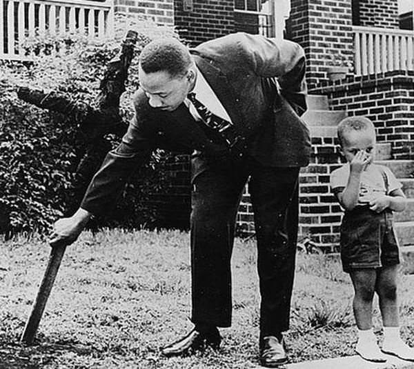 Martin Luther King Jr. removing a burned cross from his yard with his son in 1960.