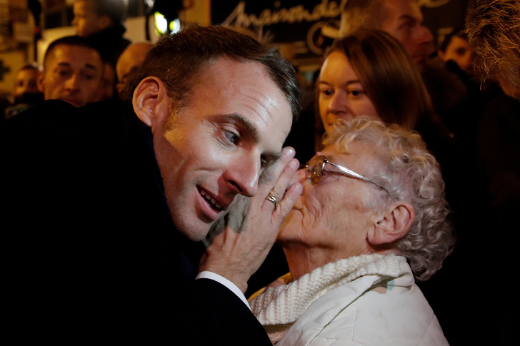 French president Emmanuel Macron is listening to an elderly woman in the crowd.