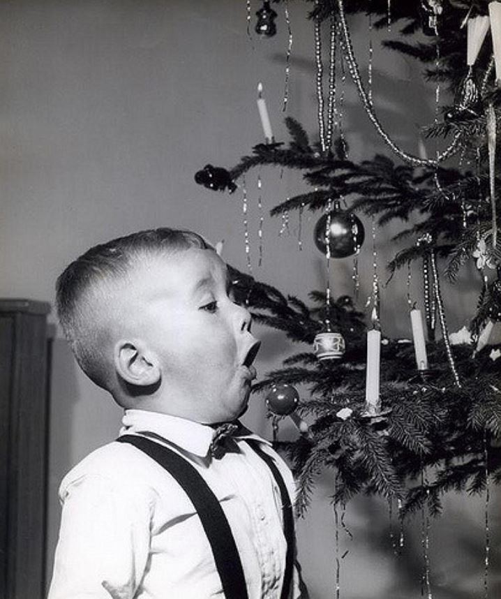 A boy blowing out a Christmas tree candle