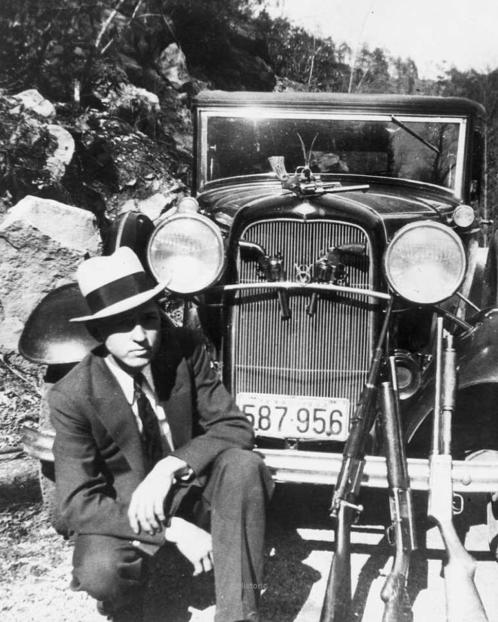Clyde Barrow, of Bonnie & Clyde fame, poses with his car and guns in Joplin, Missouri 1933