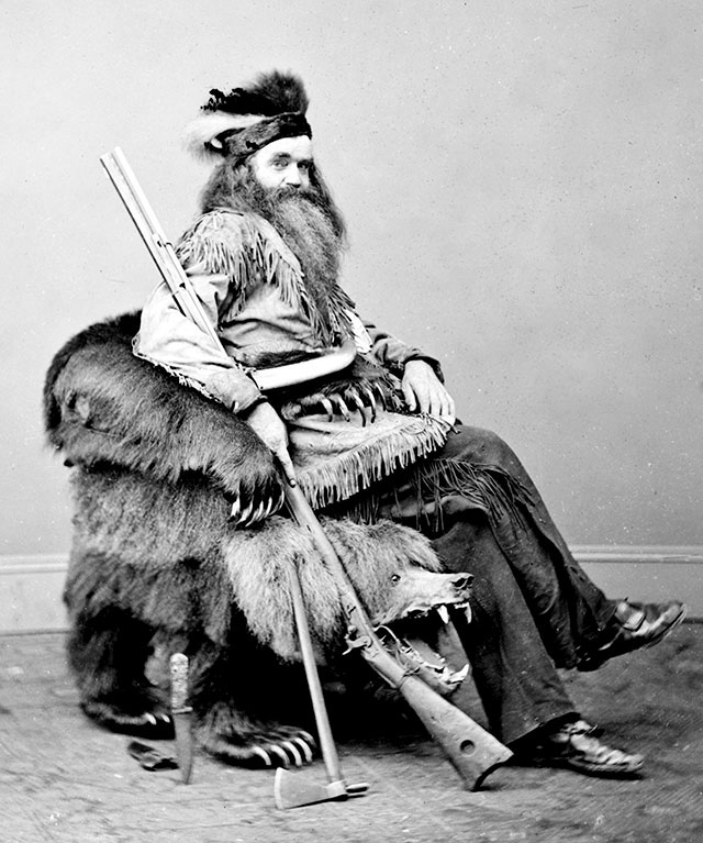 Seth Kinman, a hunter, entertainer, and one of the earliest settlers of Humboldt County, California, sitting on a chair he gave to President Johnson made out of a grizzly bear. 1865