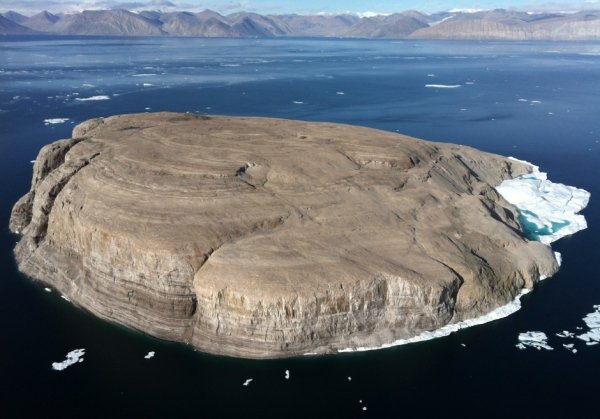 This is Hans Island. A few times a year Canada and Denmark will place their flag on it and claim it as theirs back and forth, always leaving a bottle of liquor for the other country.