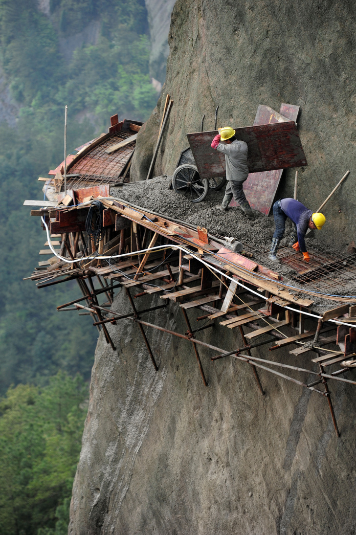 Chinese men working on building a new road on the side of a mountain to attract tourists.