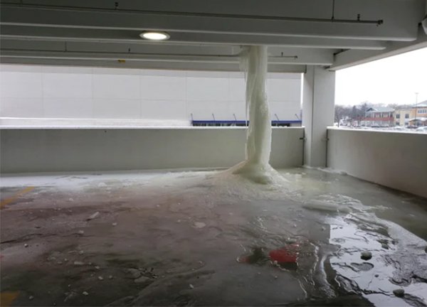 Frozen waterfall from a leaky pipe in the corner of a parking garage