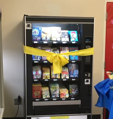 Kids earn free tokens to get a book from a vending machine.