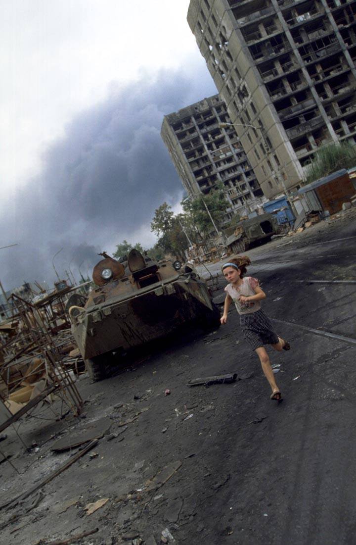 A young girl runs past a burned out Russian APC during the Battle of Grozny.