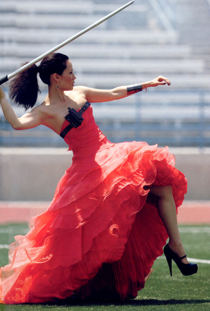 Lucy Liu throwing a javelin in a formal gown and high heels