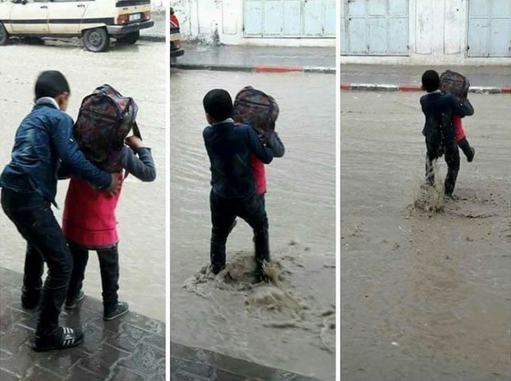 A boy helps his sister during a flood.