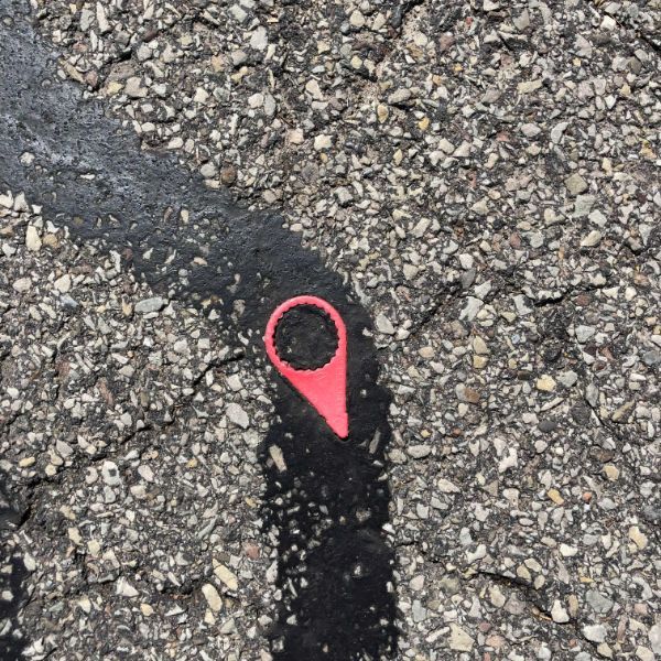 Piece of plastic stuck in the pavement looks like the google maps icon.