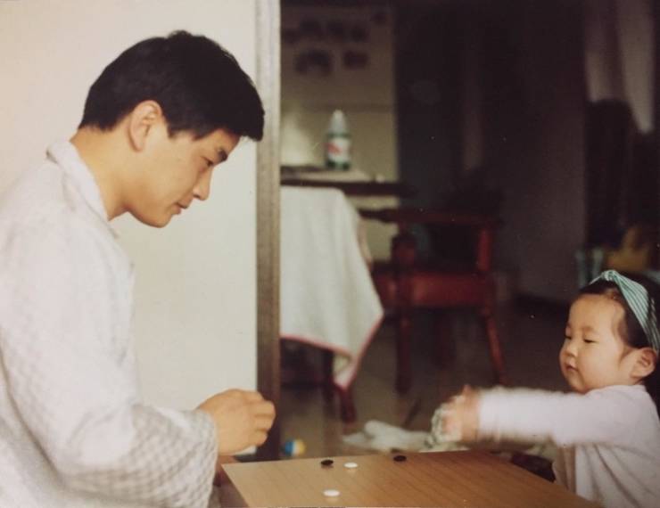 Dad teaches his daughter how to play a traditional Chinese board game.