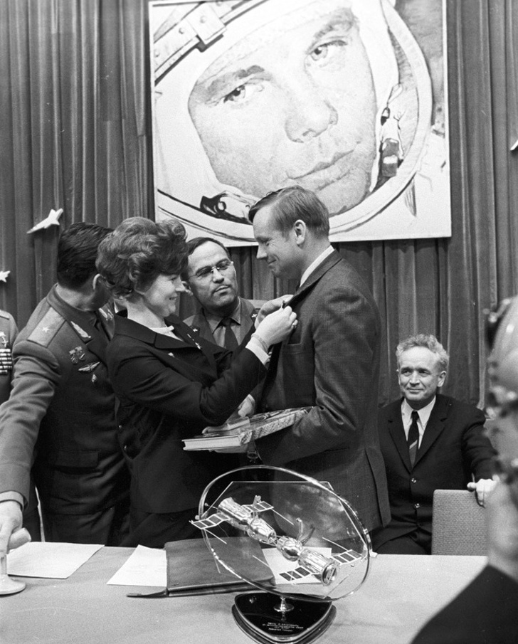 Female cosmonaut giving a badge to Neil Armstrong.