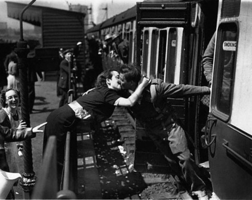 A woman kissing a soldier returning from WWII.