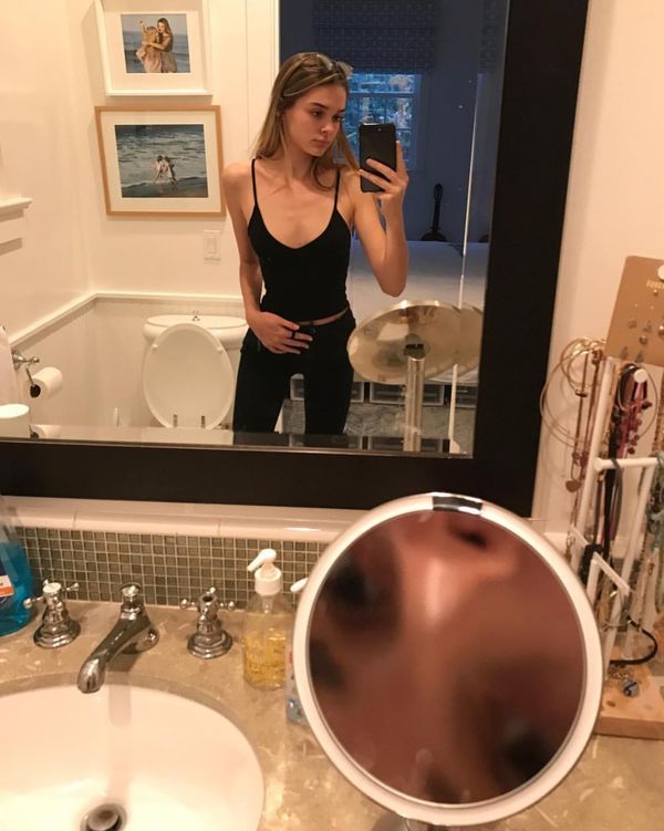 Hot girl taking a selfie in a bathroom, her face is reflected in a magnifying mirror