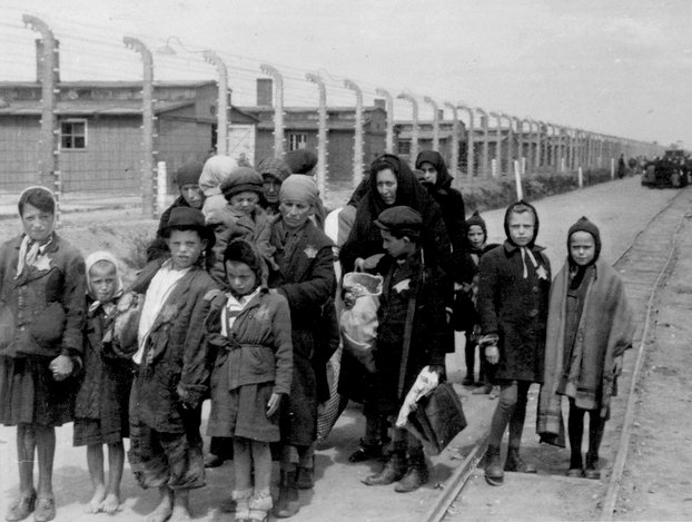 Jewish mothers and children walk past gas chambers.
