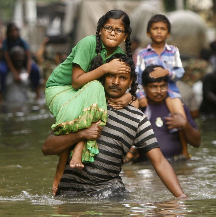 Dads carrying their children through flood waters.