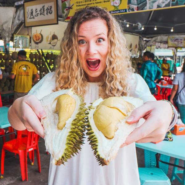 bizare things found in asia - woman holding up a stinky durian fruit