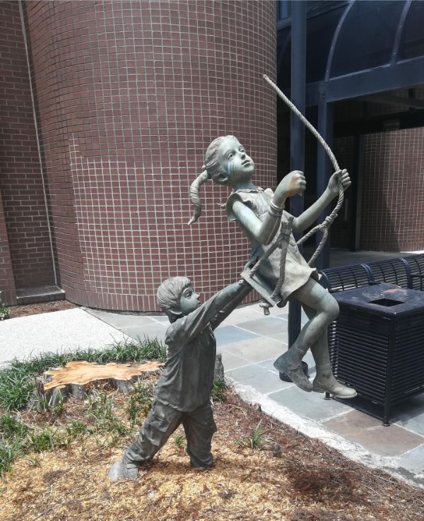 sculpture of kids swinging from a tree