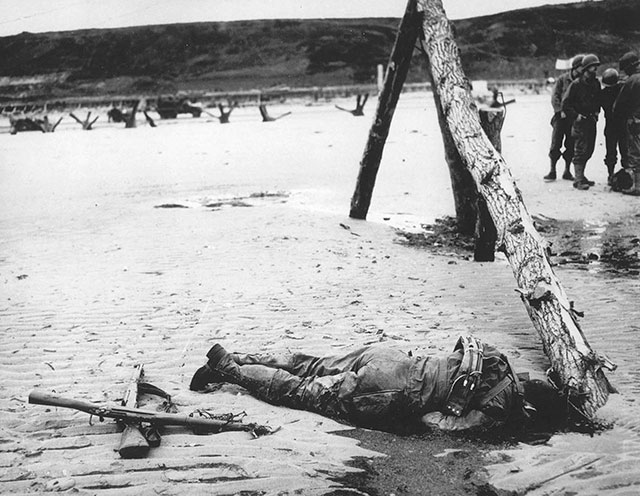 An American soldier who died in combat during the Allied invasion lies on the beach of the Normandy coast.