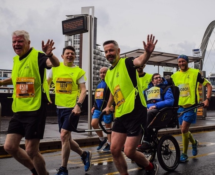 Group of runners help disabled kid get across the finish line.