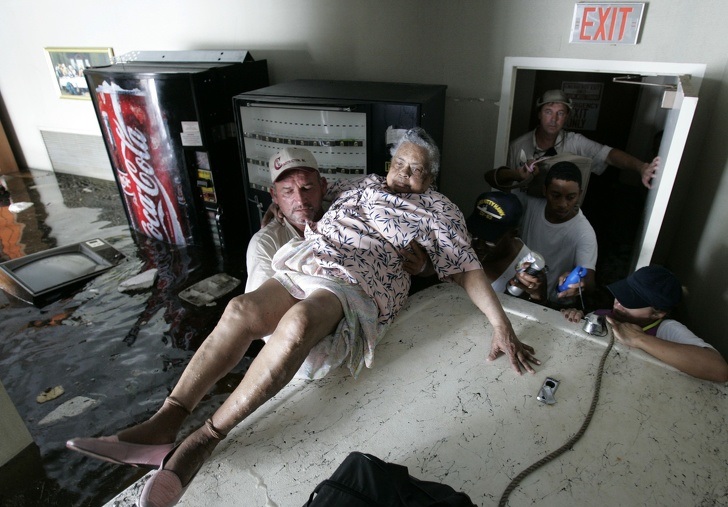 An elderly woman being carried out of a flooded house.