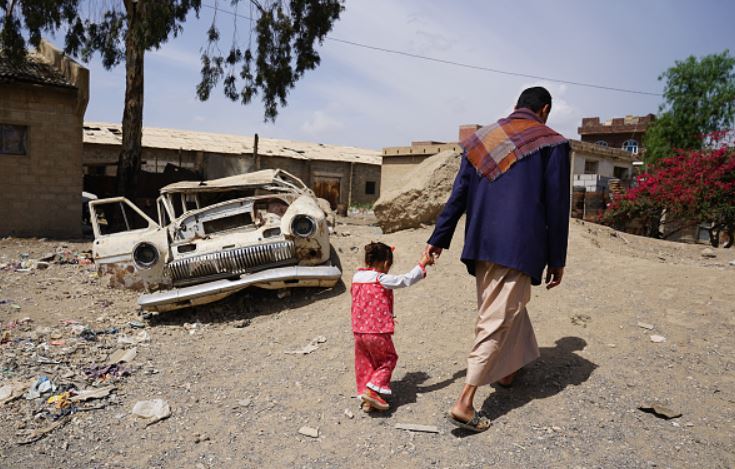 A man walking with his daughter in a slum in Yemen.