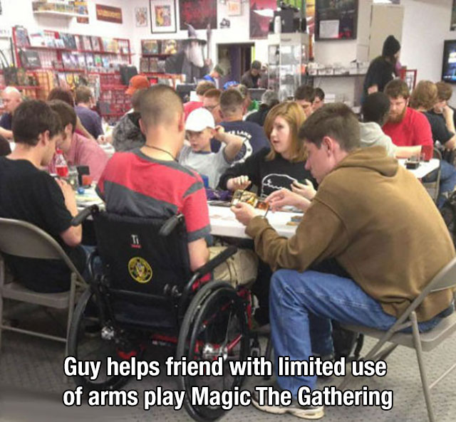 Kindness - Guy helps friend with limited use of arms play Magic The Gathering