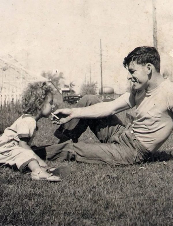 Man hands young girl a cigarette in the 1950s.