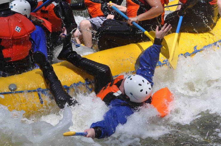 White water rafter falling off the side of a raft