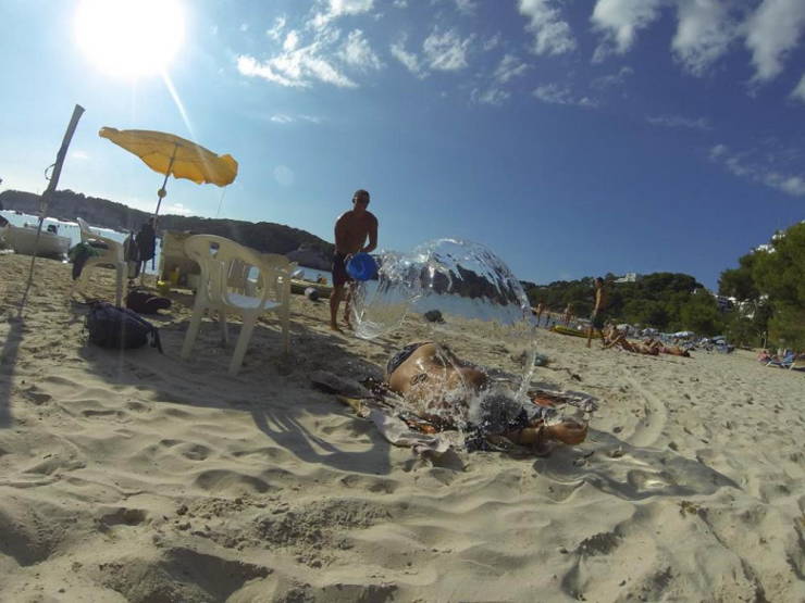 Perfectly timed photo of a man throwing water onto a water laying on the beach