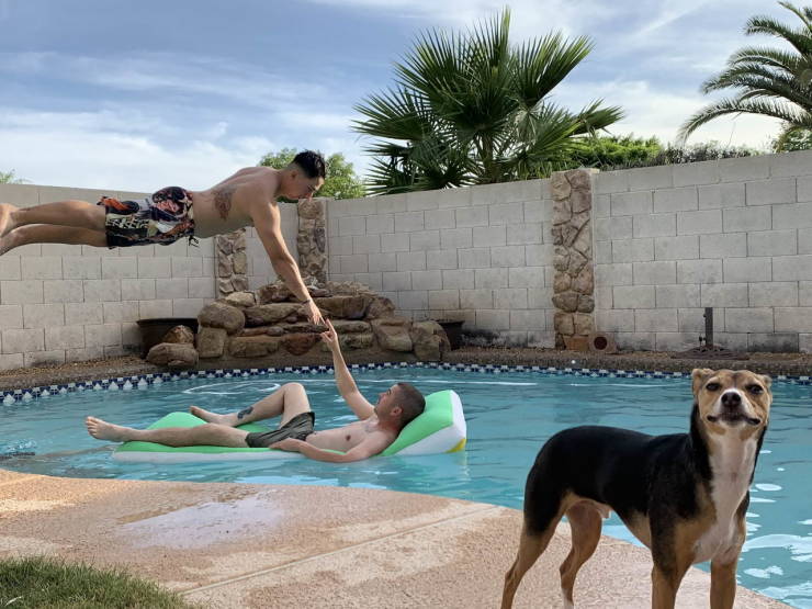 Well timed photo of a man jumping over another man into a pool touching fingers to look like Michelangelo's creation scene