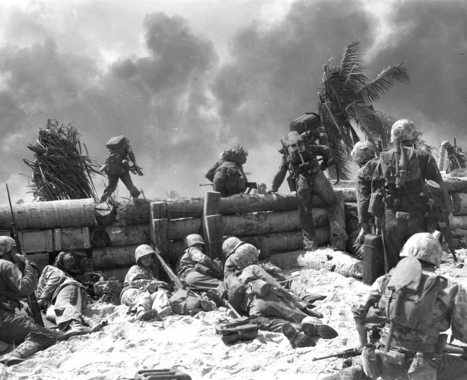 U.S. Marines move out from behind a log seawall during the Battle of Tarawa (November, 1943).