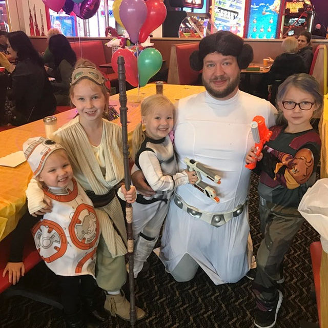 family of star wars enthusiasts with dad dressed as Leia