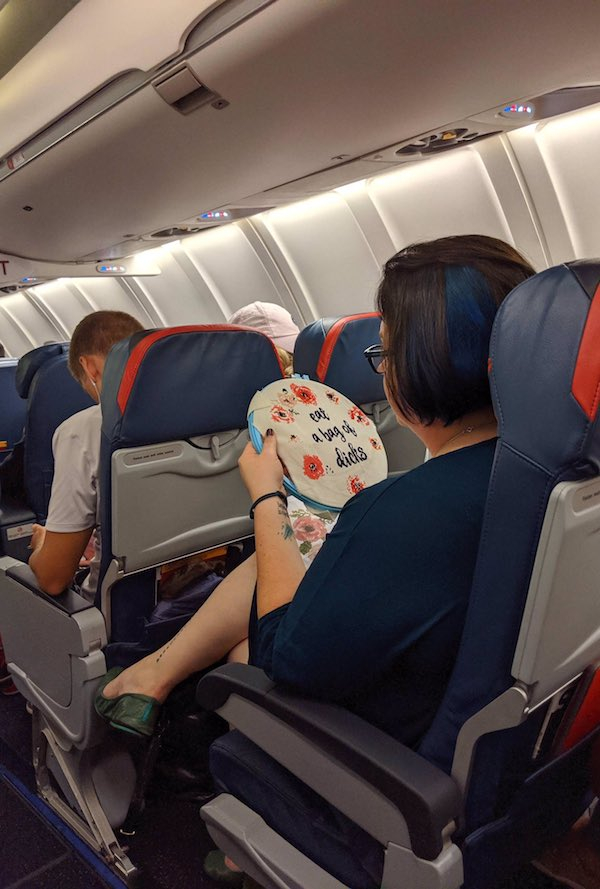 random lady cross stitching on plane - a bas