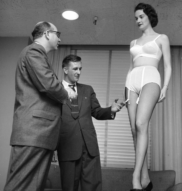 A buyer looking at a new bra and panty set being modeled for him, circa 1955