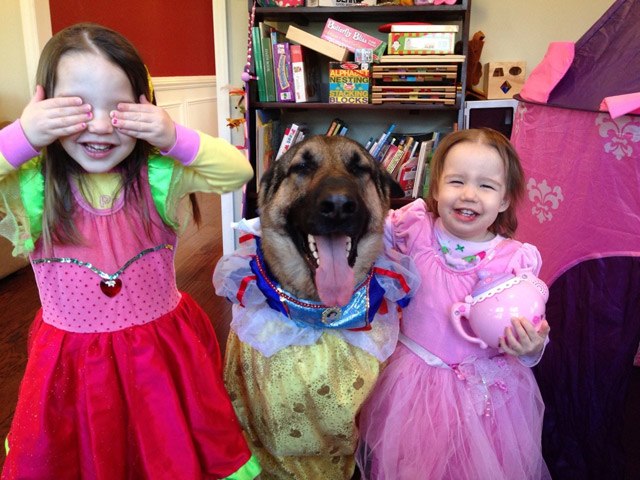 wholesome pic of two little girls wearing costume with their dog aslo
