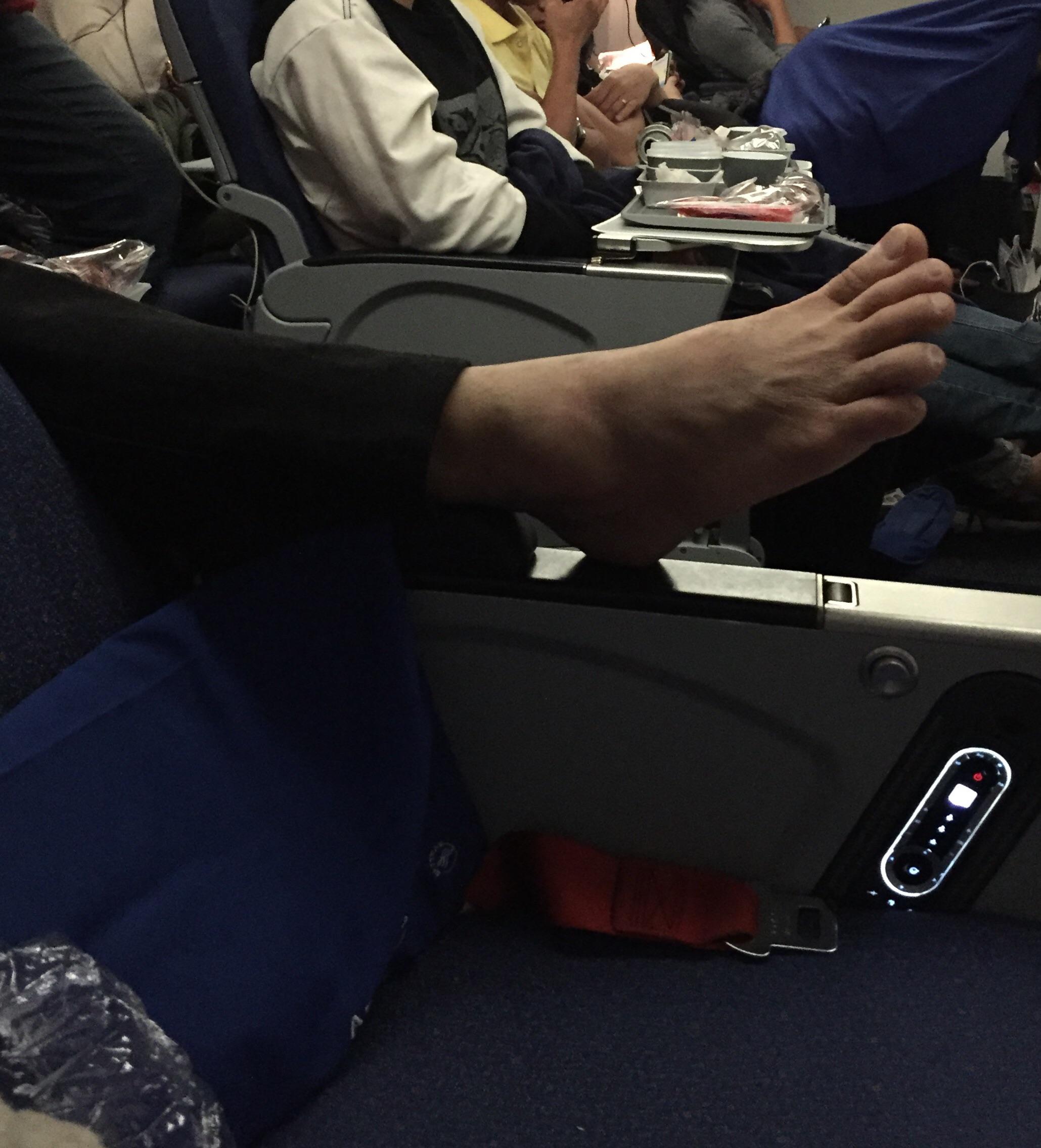 trashy person with their foot in a stanger's armrest on an airplane