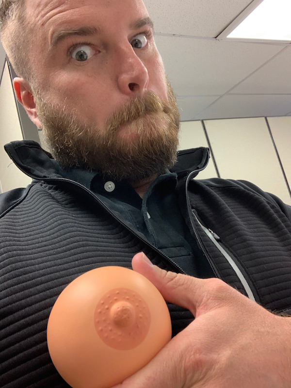 man holding a fake boob