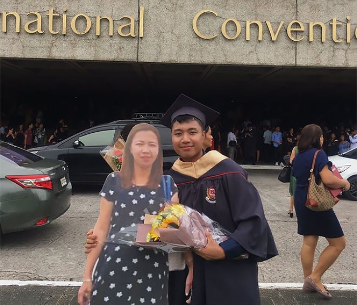 A boy posing with a life-sized cutout of his deceased mother at his graduation ceremony. His mother promised him that she’d be at his graduation, but she died of pneumonia last year.