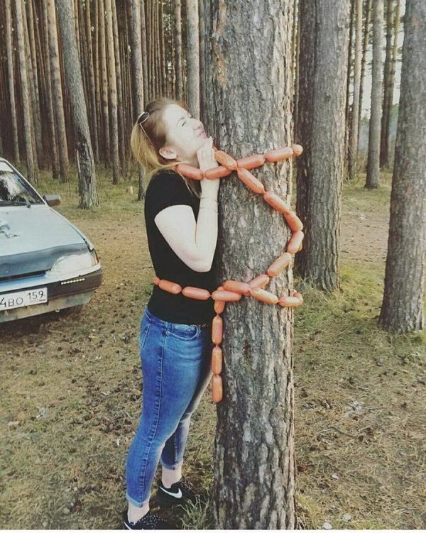 Woman tied to a tree with a long rope of sausages