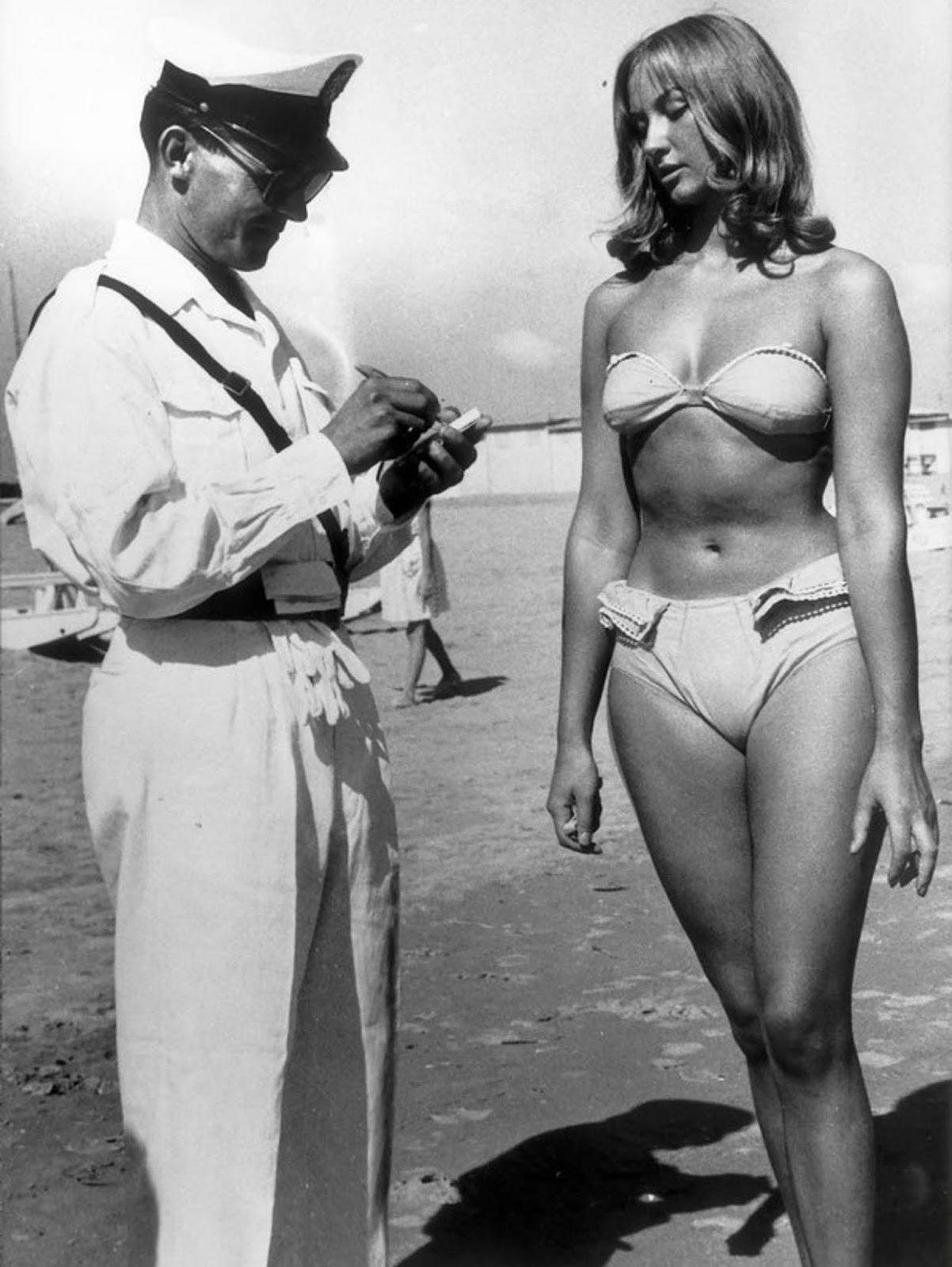 A police officer issuing a woman for wearing a bikini on the beach in 1957 Italy.