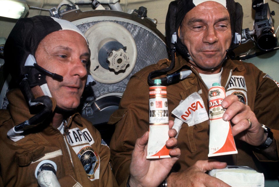 Astronauts Deke Slayton and Thomas Stafford toast to a successful docking during the Apollo/Soyuz "handshake in space." Their cosmonaut counterparts gave them tubes of Russian Vodka to celebrate — but after a drink, the Americans realized it actually contained borscht. (Earth Orbit,1975)