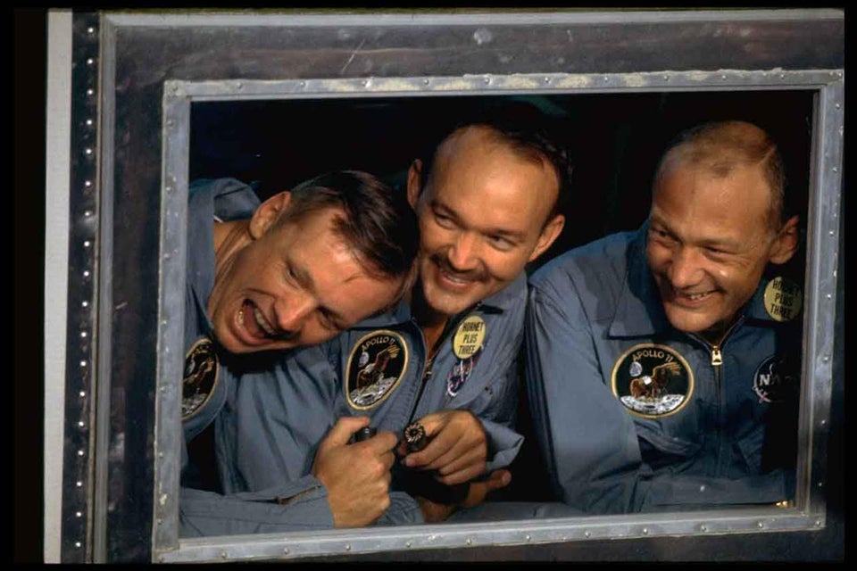 Apollo 11 astronauts (R-L) Aldrin, Collins, & Armstrong peering out the window of the quarantine room aboard recovery ship USS Hornet following splashdown fr. historic moon mission, july 1969.