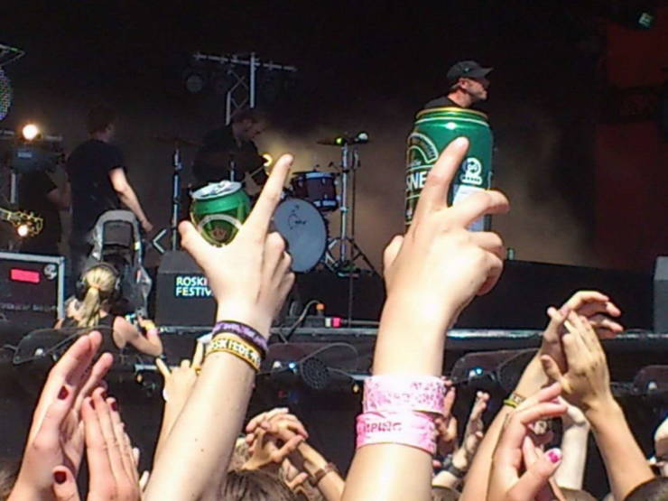 person holding up a beer can at a concert