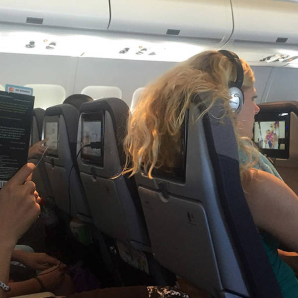 Womans hair hanging over her airplane seat covering the screen of the person behind her