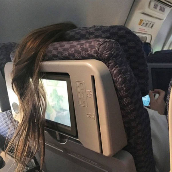 Ponytail hanging over the seat on an airplane blocking the tv of the person sitting behind them